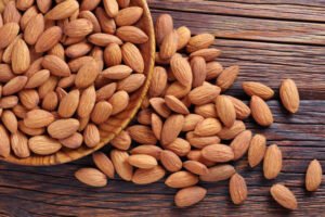close up of almonds in a wooden plate on the table, top view