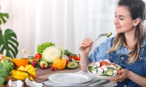 young and happy woman eating salad at the table